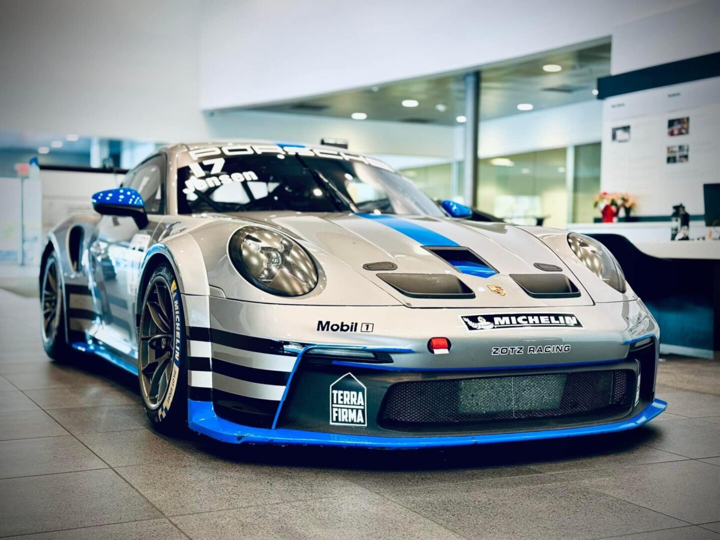 A silver and blue car is parked in a showroom.