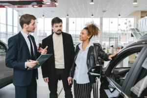 Car dealership discussion with three people present.