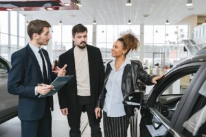 Car dealership discussion with three people.