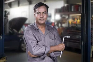 Mechanic in garage holding a tool.